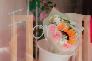 A vibrant bouquet of flowers behind a glass with 'Flores' written on it, softly lit.